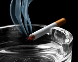 Lit cigarette smoking on ashtray