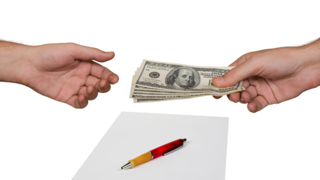 Image of hands exchanging money for a contract