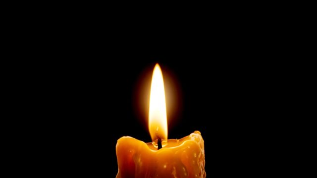 Orange candle lit against a black background