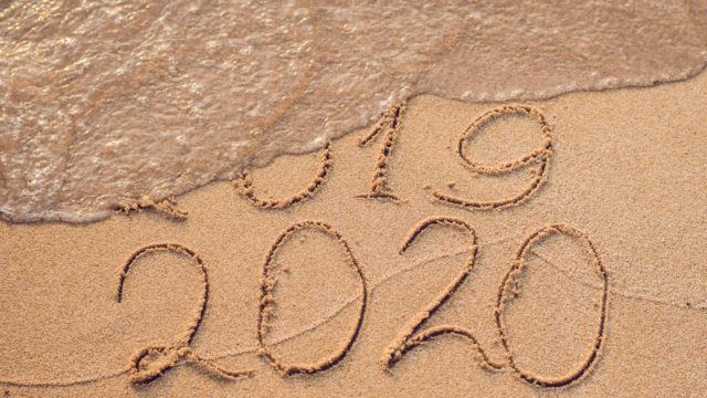 2020 written in the sand with 2019 being washed away by a wave