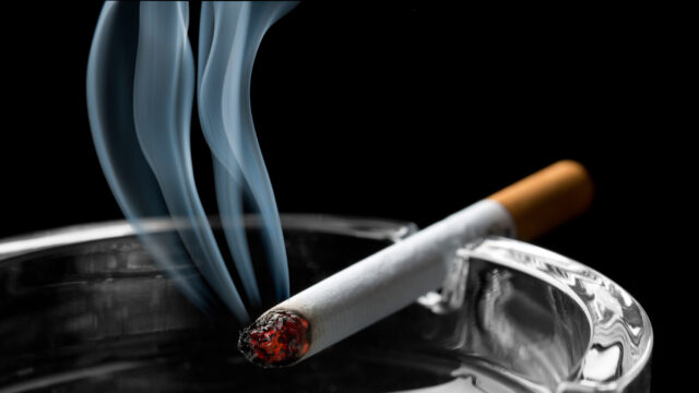 Lit cigarette smoking on ashtray